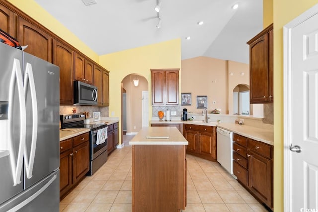 kitchen with light tile patterned floors, stainless steel appliances, arched walkways, and a center island