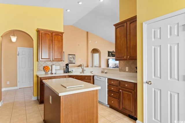 kitchen with arched walkways, dishwasher, lofted ceiling, and a sink