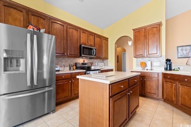 kitchen with light tile patterned floors, appliances with stainless steel finishes, a kitchen island, and light countertops