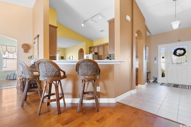 interior space featuring a breakfast bar, light wood-type flooring, arched walkways, and brown cabinets