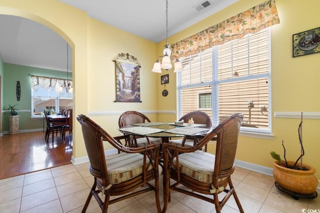 dining space featuring tile patterned flooring, visible vents, arched walkways, and baseboards