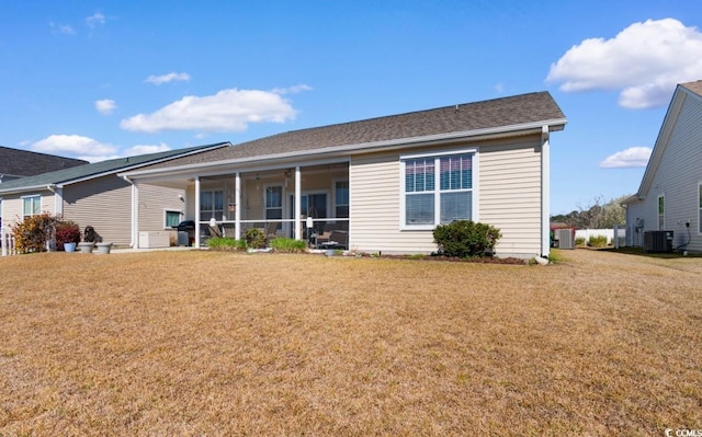 rear view of house featuring central air condition unit, a lawn, and a sunroom