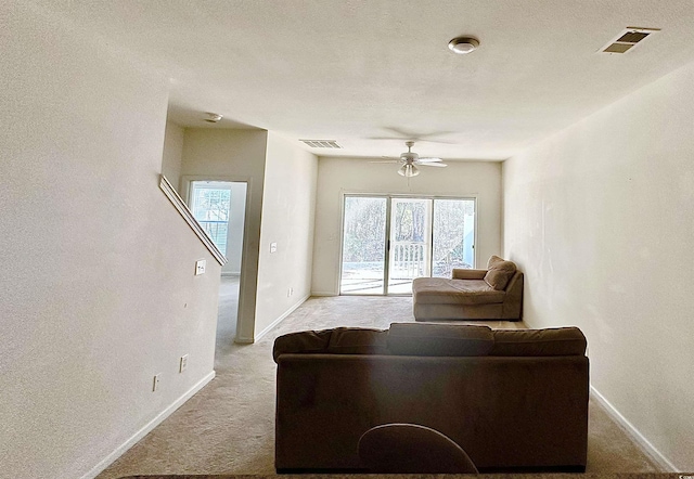 carpeted living area with baseboards, visible vents, and ceiling fan