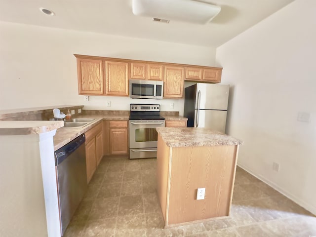 kitchen featuring visible vents, a sink, a kitchen island, appliances with stainless steel finishes, and light countertops