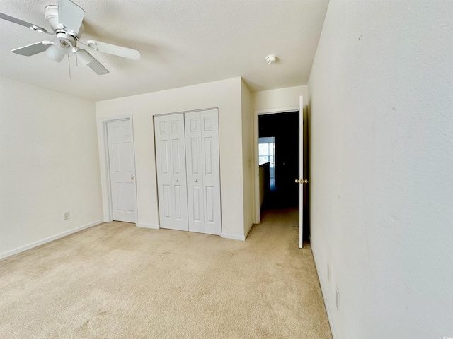 unfurnished bedroom with baseboards, light colored carpet, and a ceiling fan