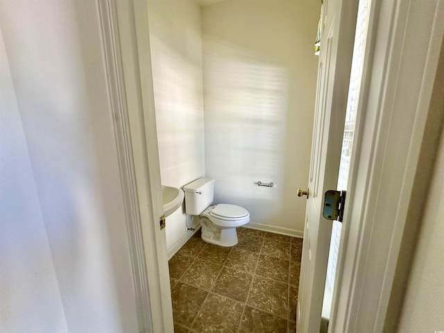 bathroom featuring baseboards and toilet