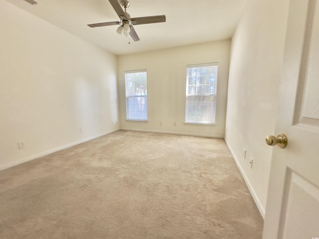 empty room featuring light carpet, ceiling fan, and baseboards