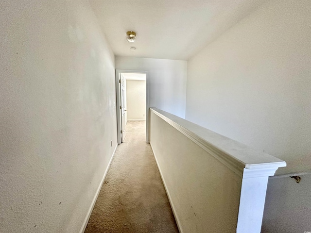 corridor featuring baseboards, light carpet, and an upstairs landing