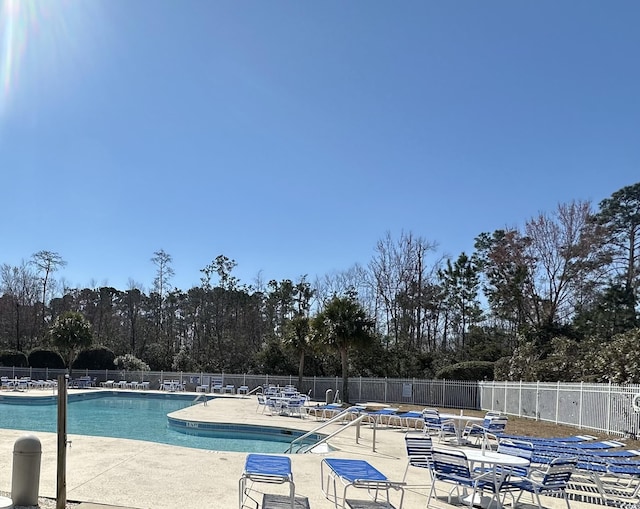 community pool with a patio and fence