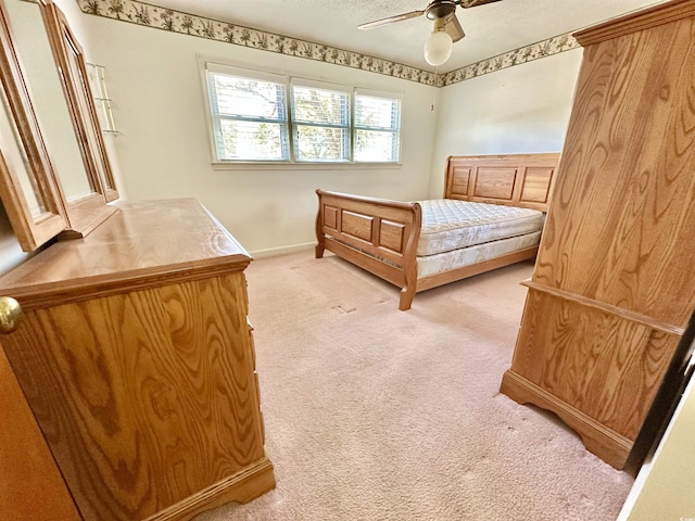 bedroom featuring baseboards, light colored carpet, ceiling fan, and a textured ceiling