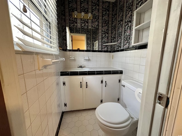 bathroom with vanity, wallpapered walls, tile patterned floors, toilet, and tile walls