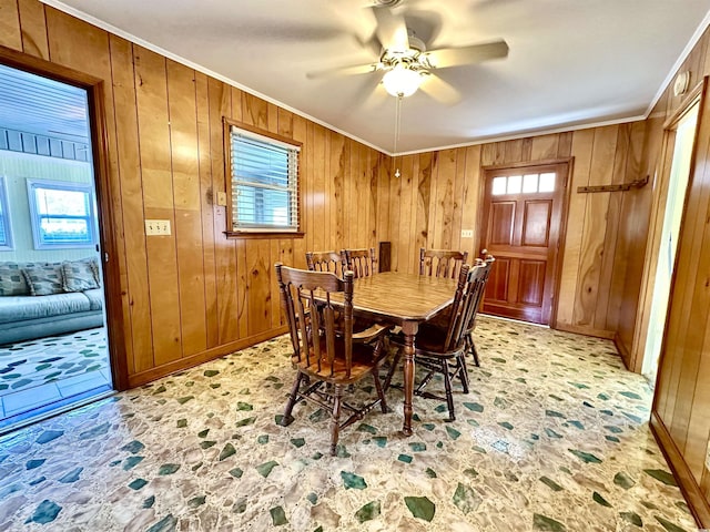 dining space featuring wooden walls, a healthy amount of sunlight, and crown molding