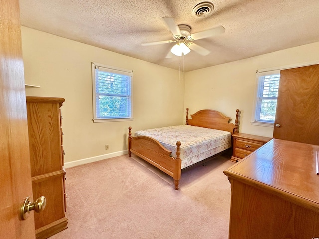 carpeted bedroom featuring ceiling fan, baseboards, visible vents, and a textured ceiling