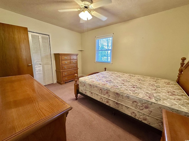 bedroom with a closet, light carpet, a textured ceiling, and a ceiling fan