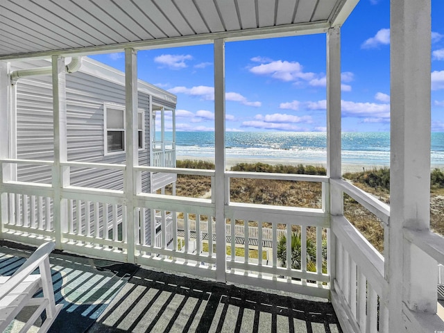 unfurnished sunroom featuring a water view and a view of the beach