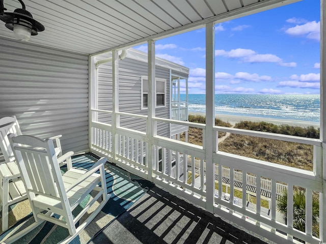 sunroom featuring a view of the beach and a water view