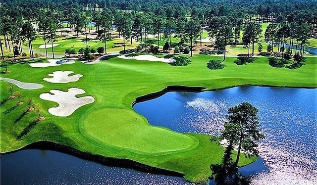 drone / aerial view featuring golf course view and a water view