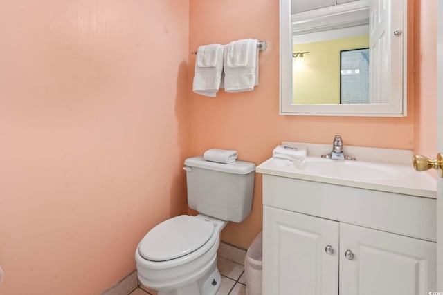 half bathroom featuring tile patterned floors, baseboards, toilet, and vanity