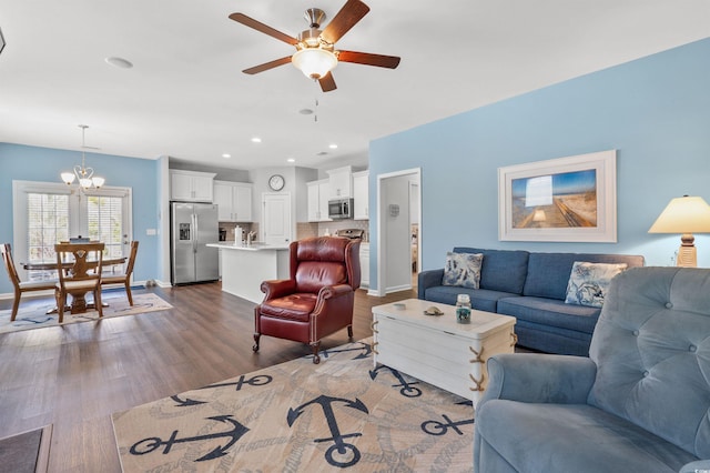 living room with recessed lighting, ceiling fan with notable chandelier, baseboards, and wood finished floors