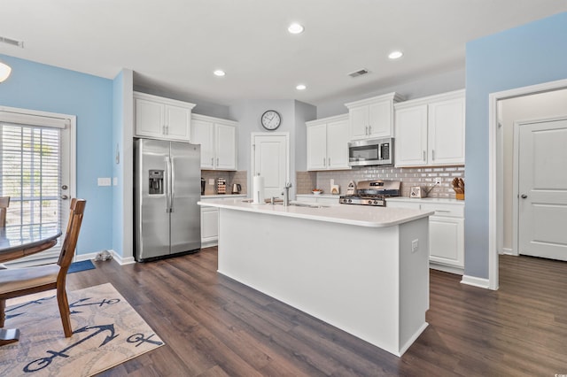 kitchen with an island with sink, stainless steel appliances, light countertops, dark wood-type flooring, and white cabinetry