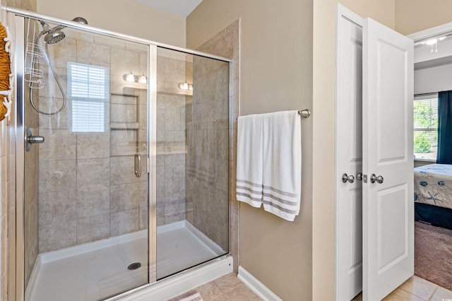 bathroom with tile patterned floors, baseboards, a shower stall, and ensuite bathroom