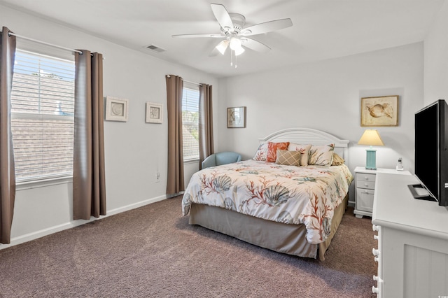 carpeted bedroom with visible vents, multiple windows, baseboards, and ceiling fan