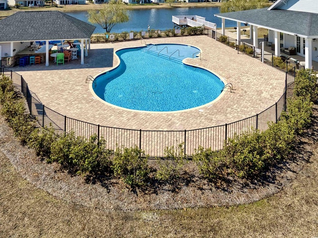 pool featuring a patio area, a water view, and fence