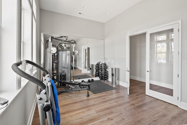 exercise room featuring wood finished floors, visible vents, french doors, and baseboards