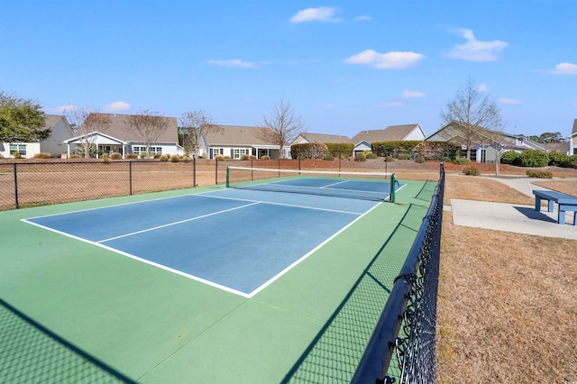 view of tennis court with a residential view and fence