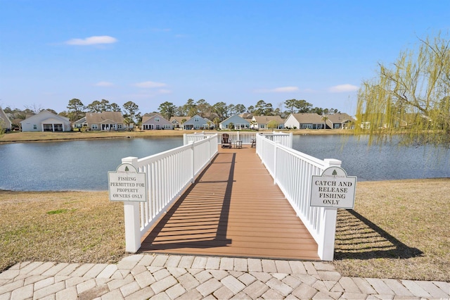 dock area with a residential view, a lawn, and a water view