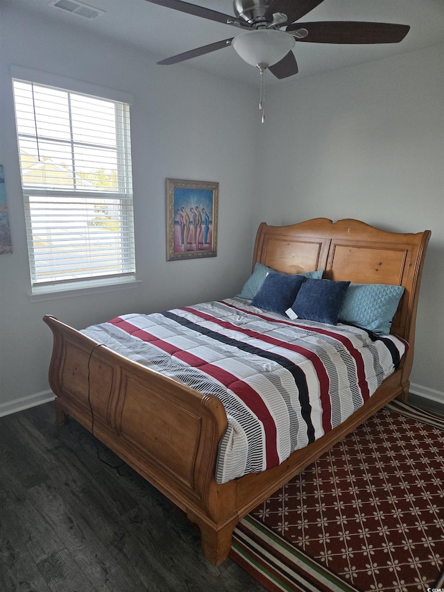 bedroom with a ceiling fan, visible vents, wood finished floors, and baseboards