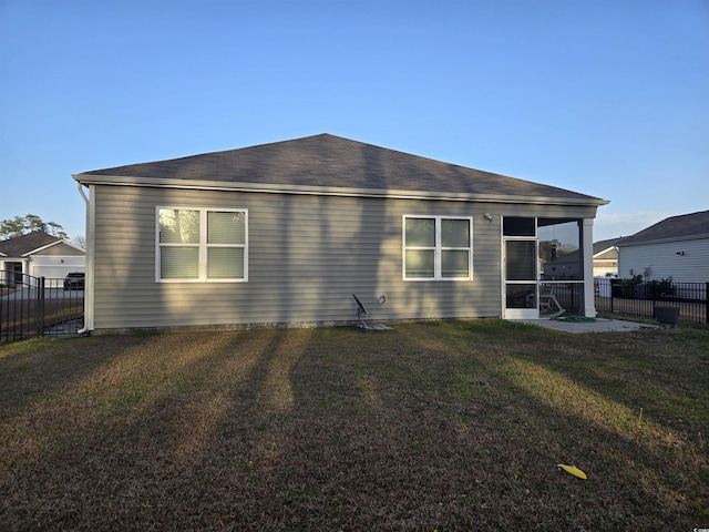 back of house with a lawn, fence, and a sunroom