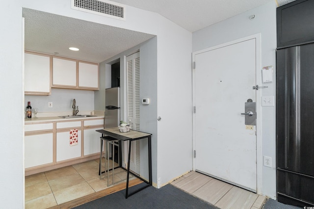 kitchen with visible vents, freestanding refrigerator, a sink, light countertops, and built in fridge