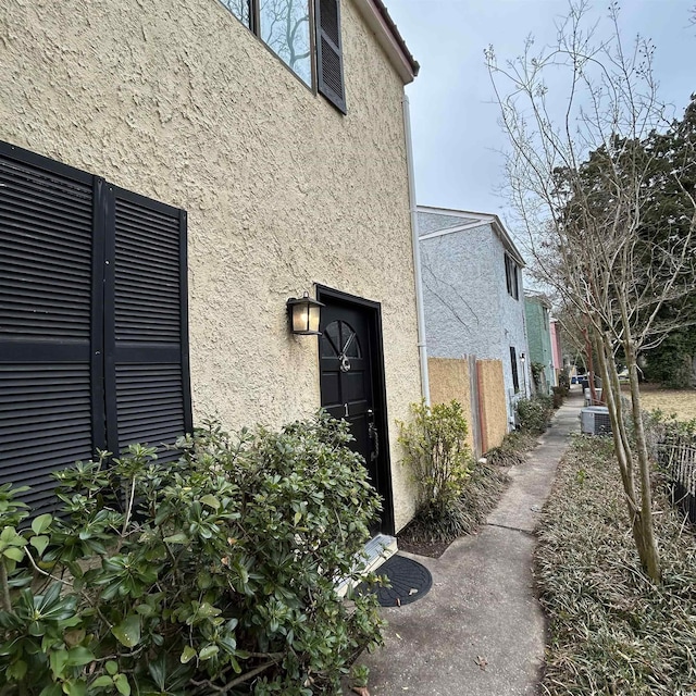 view of side of home featuring cooling unit and stucco siding