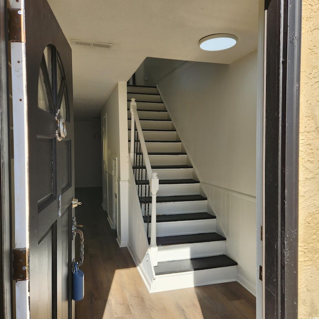 staircase featuring visible vents and wood finished floors