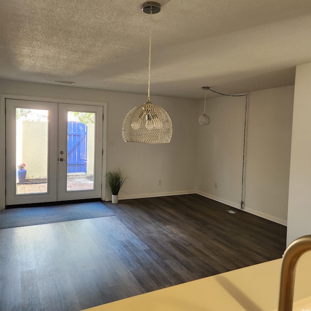 unfurnished dining area featuring dark wood-style floors, french doors, baseboards, and a textured ceiling