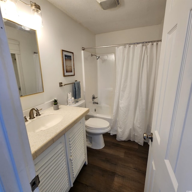 bathroom featuring visible vents, shower / bath combo with shower curtain, toilet, wood finished floors, and vanity