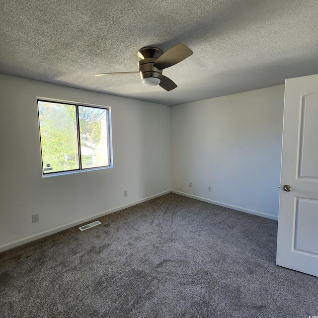 spare room with carpet, a ceiling fan, visible vents, baseboards, and a textured ceiling