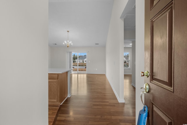 corridor with a chandelier, visible vents, baseboards, and wood finished floors