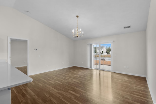 unfurnished room featuring wood finished floors, visible vents, baseboards, lofted ceiling, and a notable chandelier