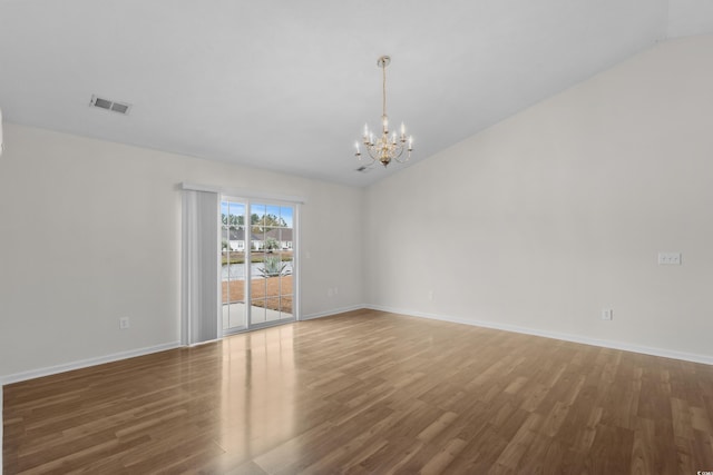 unfurnished room with visible vents, baseboards, an inviting chandelier, and wood finished floors