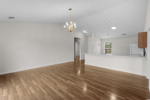 unfurnished living room featuring visible vents, lofted ceiling, baseboards, and wood finished floors