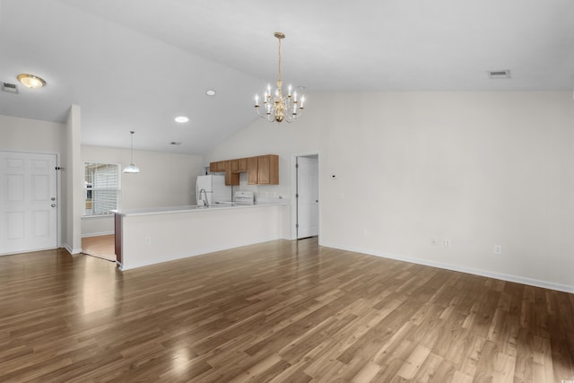 unfurnished living room featuring vaulted ceiling, visible vents, baseboards, and wood finished floors