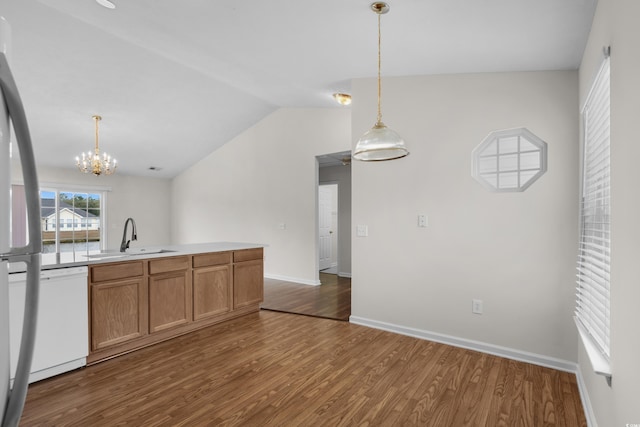 kitchen with a sink, decorative light fixtures, dark wood-style floors, white dishwasher, and vaulted ceiling