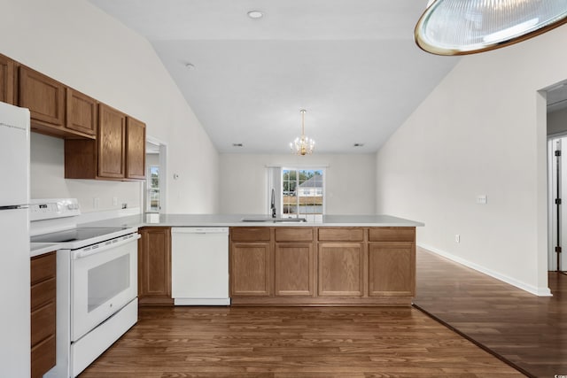 kitchen featuring white appliances, a peninsula, a sink, vaulted ceiling, and light countertops