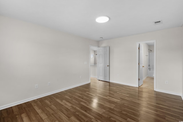 unfurnished bedroom with visible vents, wood finished floors, and baseboards