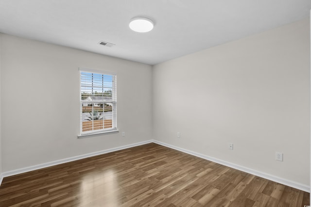 unfurnished room featuring visible vents, baseboards, and wood finished floors