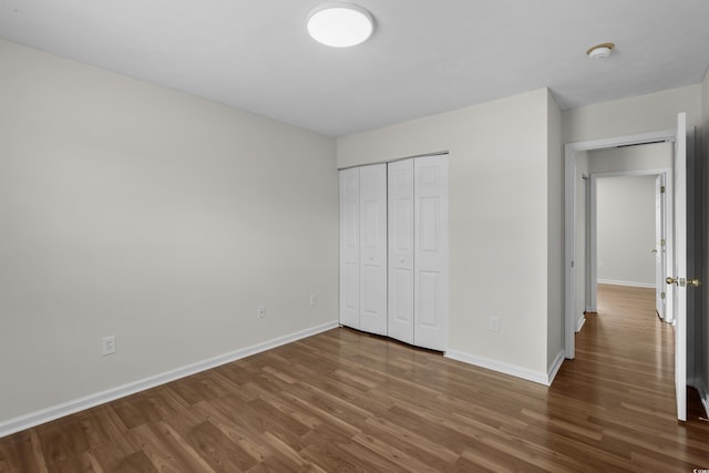 unfurnished bedroom featuring a closet, baseboards, and wood finished floors