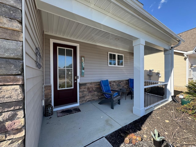 view of exterior entry featuring stone siding and a porch