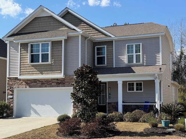 view of front facade with stone siding, an attached garage, covered porch, and driveway